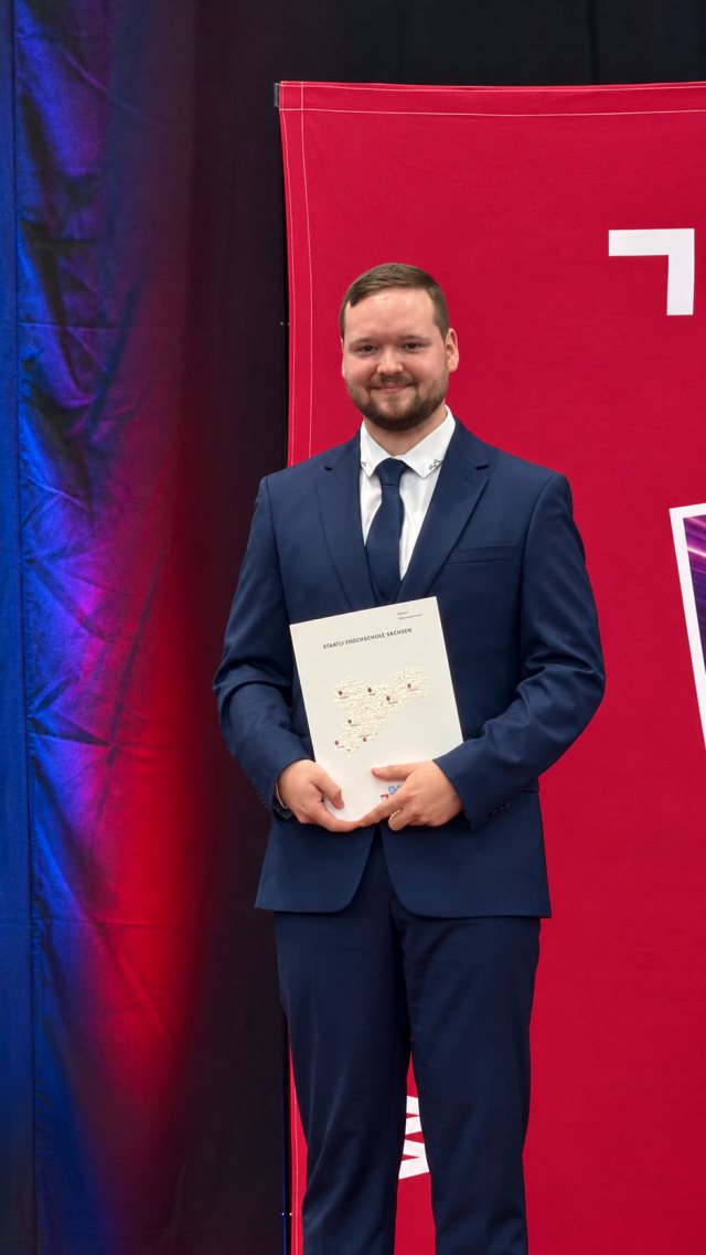 Arthur Kotsch auf der Bühne mit der Urkundenmappe der Dualen Hochschule Sachsen